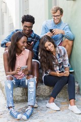 Fototapeta premium Friends sitting together using mobile phone