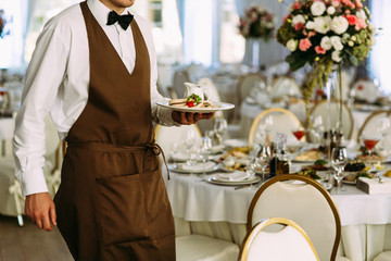 Waiter in the brown outfit serves on the wedding