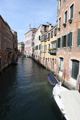 Image of a narrow Venetian Canal between old buildings.