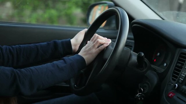 woman presses the signal to the car's steering wheel. Hands close-up.
