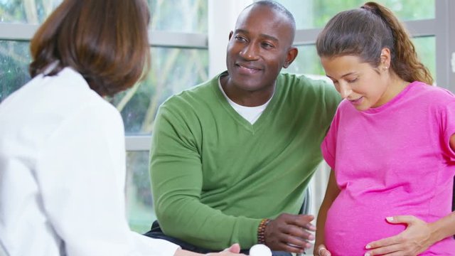  Friendly doctor talking to couple who are expecting a baby.