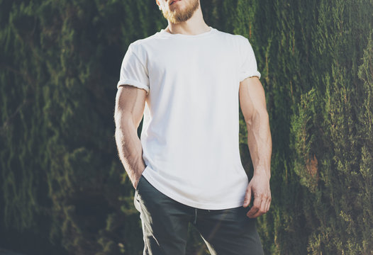 Image Bearded Muscular Man Wearing White Blank t-shirt. Green City Garden Background at sunset. Horizontal Mockup