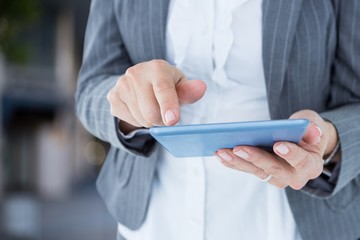 Composite image of a businesswoman who is holding a tablet