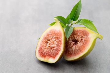 Whole figs and one fig sliced in half on top of a gray table.