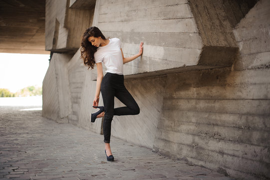 Young brunet woman standing outside in white top, jeans wearing hills . horizontal  