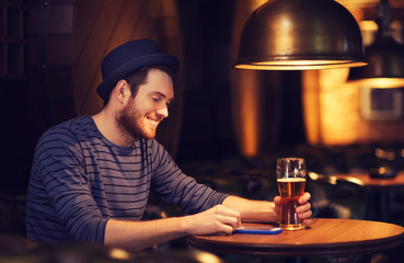 man with smartphone and beer texting at bar