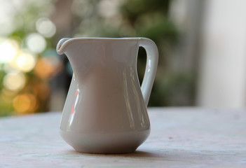 White ceramic jug on a wooden table.