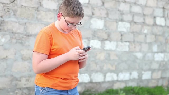 boy writes a message on a smartphone. Outdoors