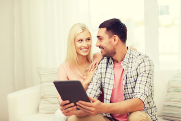 smiling happy couple with tablet pc at home