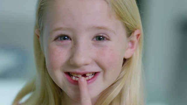  Close up portrait of little girl opening her mouth to show where she has lost one of her baby teeth. 