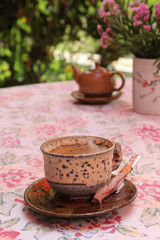 Brown ceramic coffee cup with cinnamon stick on the table.