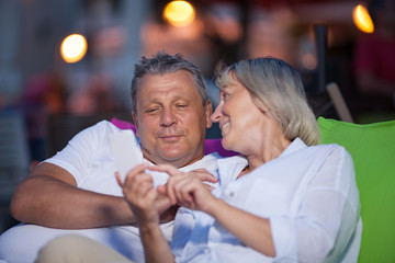 Fototapeta na wymiar Loving middle-aged couple having an intimate chat sitting close together smiling and gesturing as they spend quality time together