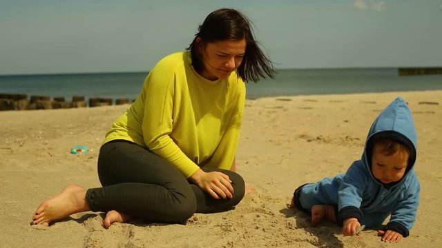 Woman plays with baby at the beach
