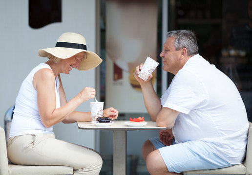 Profile of Couple Seated Opposite Each Other and Enjoying Coffee and Cake Desserts Together on Sunny Outdoor Cafe Patio