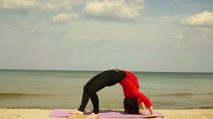 Young woman makes an exercise bridge at the beach
