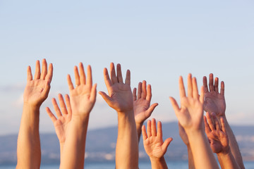 Group of people pulling hands in the air in sunlight