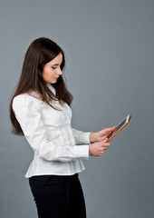 Office girl looking for her tablet. Business girl in white blouse. She stands and recalls. 