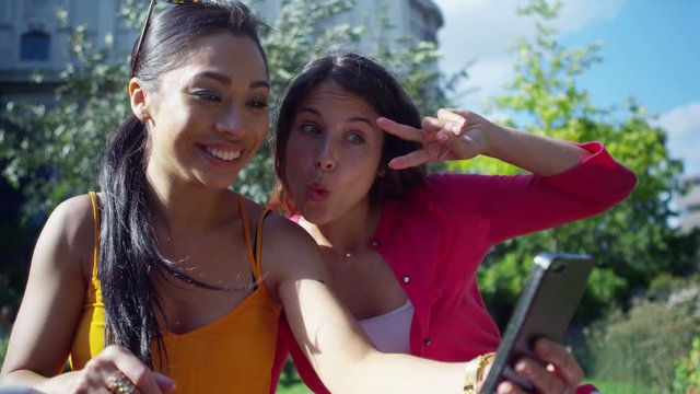  Happy attractive female friends posing for selfie outdoors in the city