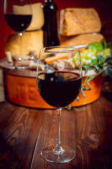 Cheese and wine on a dark table.