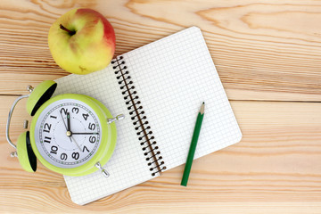 time to eat/watches, notepad, pencil and apple on wooden background top view 