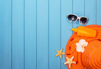 Hat, sunglasses and suntan lotion on wood background colored.