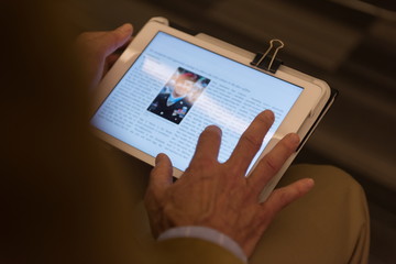 Closeup of mature hands holding tablet.