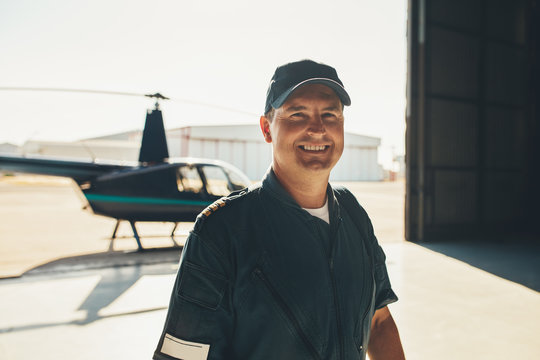 Happy male pilot standing in airplane hangar