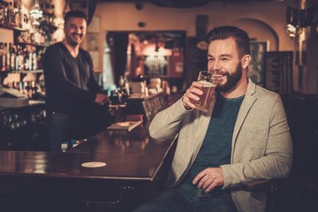 Stylish man paying for beer by cash euro to bartender in pub.