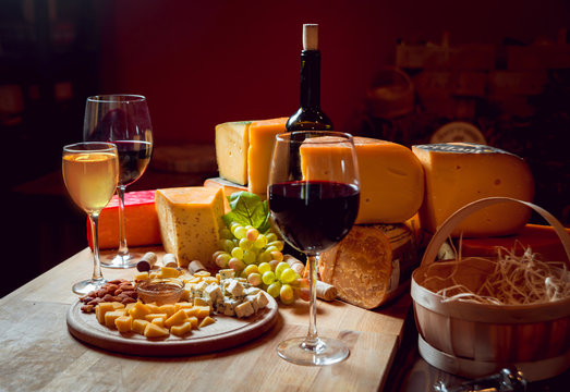 Cheese and wine on a dark table.