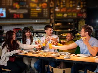 Obraz premium Cheerful multiracial friends having fun eating pizza in pizzeria.