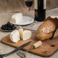 Bottle of wine, cheese and white bread are on sacking