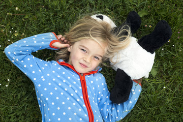Portrait of a little blond girl lying on green grass © Petr Bonek