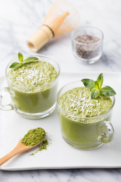 Matcha green tea chia seed pudding, dessert with fresh mint and coconut on a white stone background Healthy breakfast 