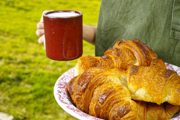 Young woman holding mug witn organic milk and fresh baked croiss
