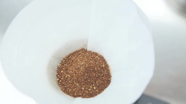 Ground coffee is poured into a bowl.