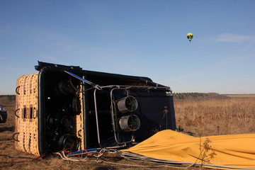 Big basket of the balloon lies on its side on the field ground a