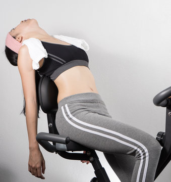 Woman sleep on exercise bike over white background