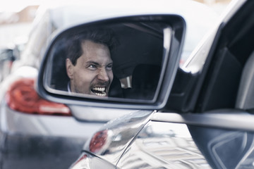 Driver with road rage reflected in wing mirror