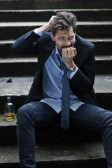 Drunk and paranoid businessman sitting on steps