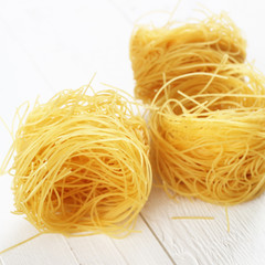 Raw tagliatelle on white wooden background