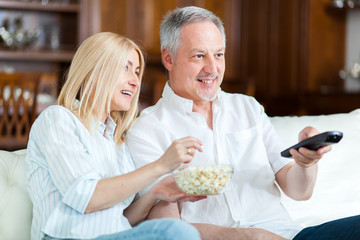  Senior couple sitting in couch and watching tv