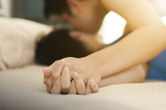Close up hands of a couple having hot sex on a bed