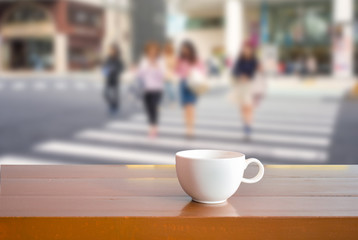 A cup on wooden table with windows city ,blur background