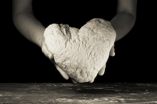 female hands hold the dough in the shape of heart
