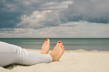 Female feet on the beach barefoot with red pedicure