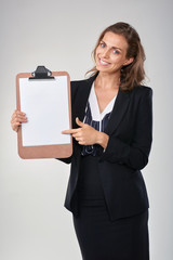 Smiling woman in business suit pointing to empty poster