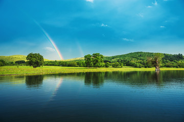 Fototapeta na wymiar Rainbow over a lake, reflected in the water