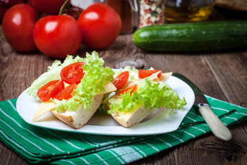 Delicious sandwich with tomatoes, cheese and lettuce on wooden table.