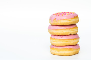 A stack of donuts with pink icing and sprinkles on an isolated, white background.