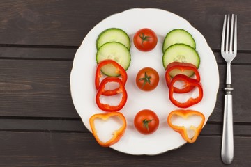 Diet food on a wooden table. Strict diet meals. Slimming diet. Tomatoes, cucumbers and peppers into a white plate.
